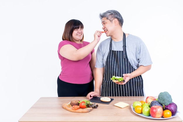 Images de portrait de femme asiatique et mari obèse sourient et bonheur Pour manger un hamburger qu'elle a préparé Sur fond blanc, à la famille asiatique et au concept de restauration rapide.