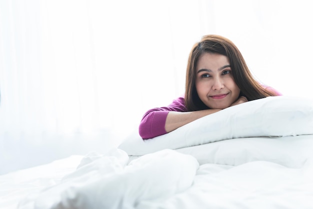 Images de portrait d'une jolie femme asiatique Allongez-vous et reposez-vous sur le lit blanc Dans sa chambre