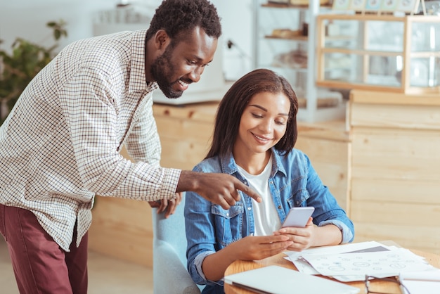 Images Sympas. Agréable Jeune Femme Assise Dans Le Café Et Montrant à Son Collègue Masculin Des Photos De Vacances Pendant La Pause Au Travail Tandis Que L'homme Montrant De L'excitation