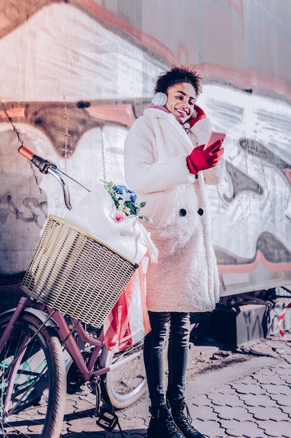 Photo imagine seulement. jolie femme internationale exprimant la positivité en se tenant près de son vélo