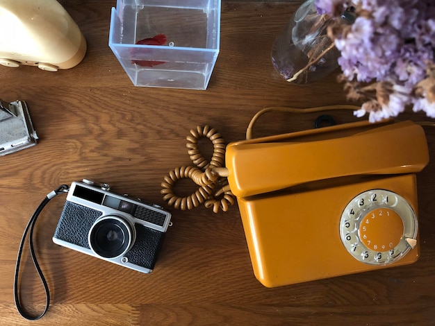 Photo immédiatement au-dessus de la caméra à l'ancienne et du téléphone rotatif sur une table en bois