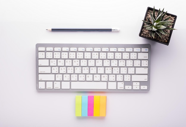 Immédiatement au-dessus de la photo d'un clavier d'ordinateur avec des fournitures de bureau et une plante sur fond blanc