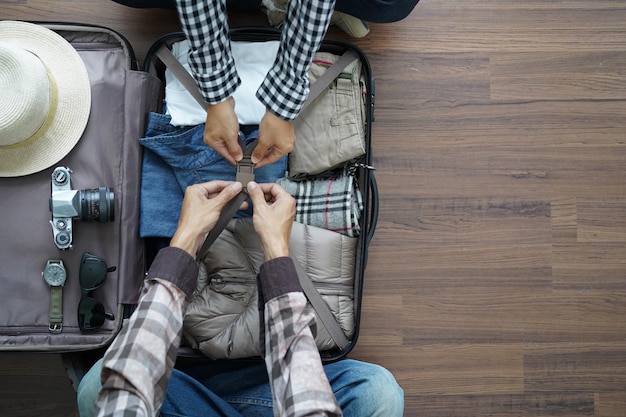 Photo immédiatement au-dessus de la photo de deux personnes emballant une valise alors qu'elles sont assises sur le sol en bois dur