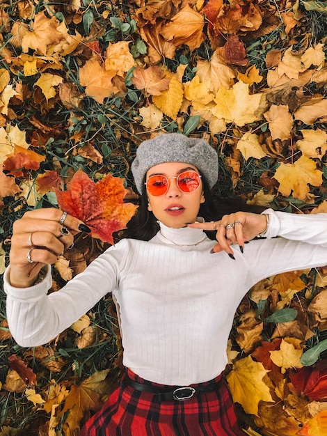 Photo immédiatement au-dessus de la photo d'une femme allongée tenant une feuille d'érable