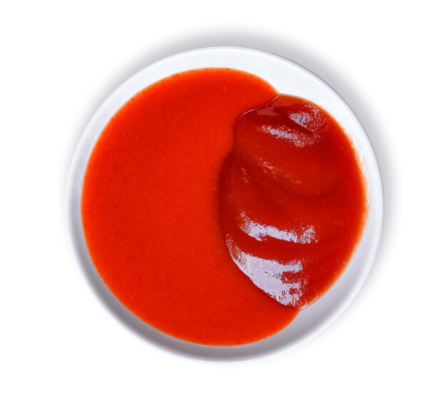 Photo immédiatement au-dessus de la prise de sauce tomate dans une assiette sur fond blanc