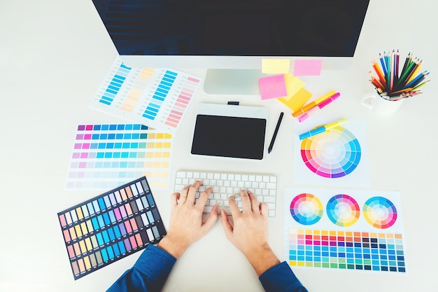 Immédiatement au-dessus de la prise de vue d'une personne d'occupation créative utilisant un ordinateur avec un échantillon de couleur sur la table