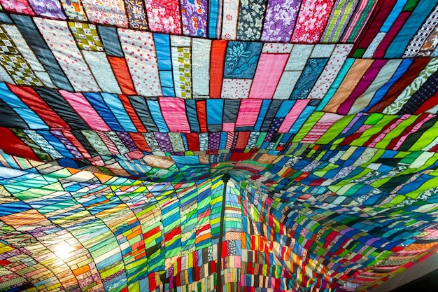 Un immense tissu artistique coloré composé d'une combinaison de pièces colorées de vêtements inutilisés et collectés par un tailleur