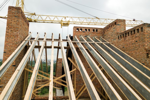 Immeuble d'appartements en brique inachevé avec structure de toit en bois en construction.