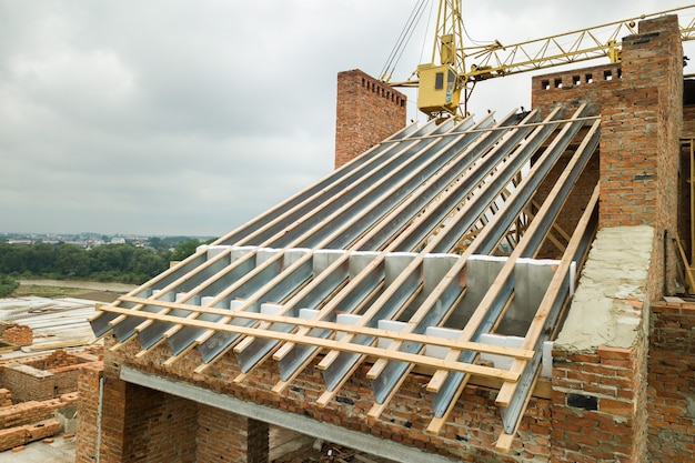 Immeuble d'appartements en brique inachevé avec structure de toit en bois en construction.