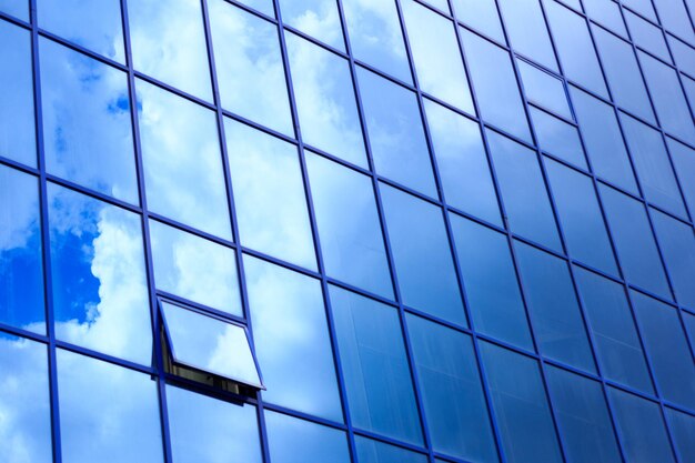 Immeuble de bureaux moderne avec fenêtres ouvertes et nuages réfléchissants dans la façade en verre