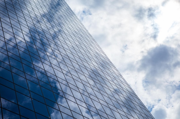 Immeuble de bureaux moderne en verre fumé contre un ciel bleu nuageux