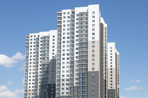 Immeuble multifamilial blanc-gris élevé contre le ciel bleu