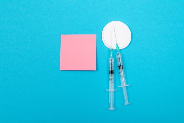 Immunologie de la vaccination ou concept de revaccination deux seringues médicales jetables allongées sur une table bleue ...