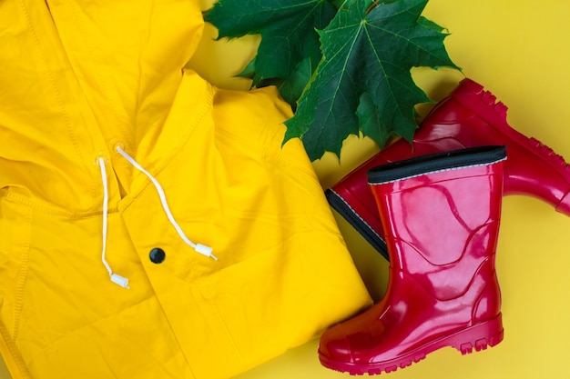 Un imperméable jaune et des bottes en caoutchouc rouges. Vente d'imperméable de feuilles d'érable d'automne