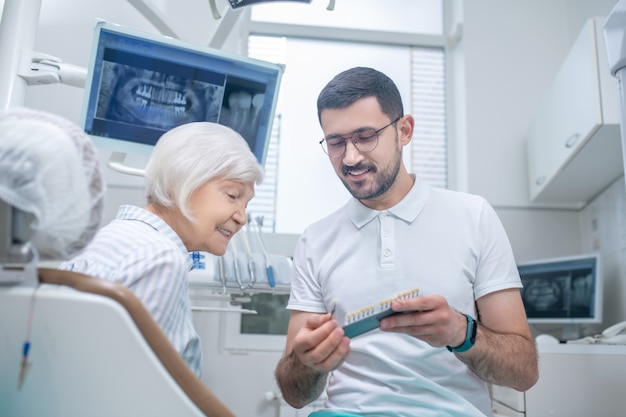 Implants dentaires. Jeune dentiste masculin choisissant l'implant dentaire avec son patient