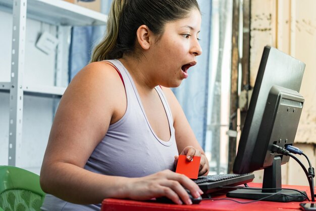 Impressionné jeune femme avec sa bouche ouverte à la recherche de promotions en ligne