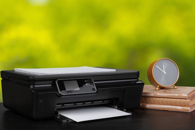 Imprimante domestique compacte sur le bureau avec des livres sur fond flou