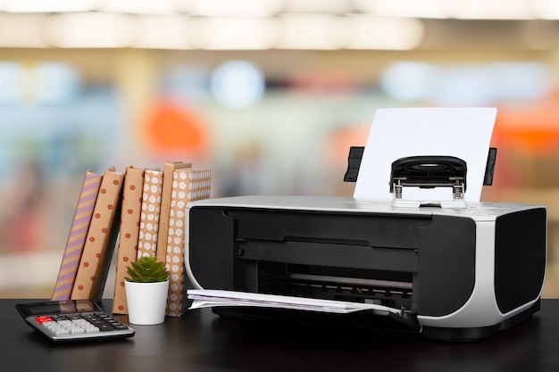 Imprimante domestique compacte sur le bureau avec des livres sur fond flou