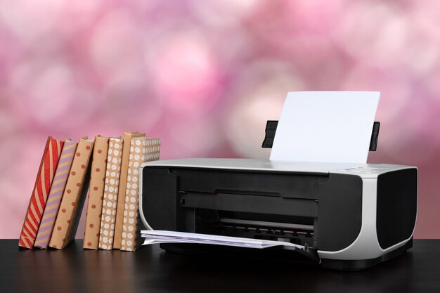 Imprimante domestique compacte sur le bureau avec des livres sur fond flou