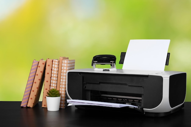 Imprimante domestique compacte sur le bureau avec des livres sur fond flou