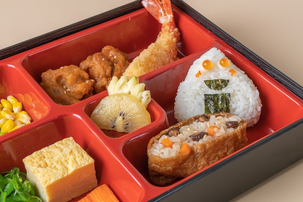 Photo (inari sushi) riz à sushi enveloppé dans du tofu séché avec crevettes frites et poulet frit dans un ensemble bento - cuisine japonaise