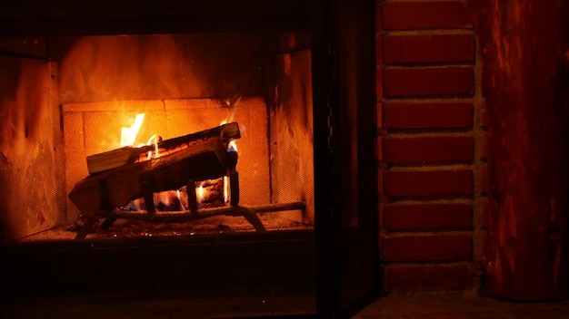 Incendie dans une cheminée en brique brûlant du bois brûlant dans un lodge ou une cabine confortable