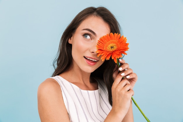 Incroyable belle jeune femme isolée mur tenant une fleur.