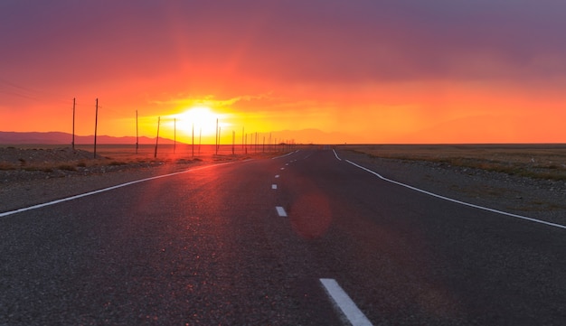 Incroyable coucher de soleil rouge sur une route goudronnée infiniment longue dans la République de l'Altaï