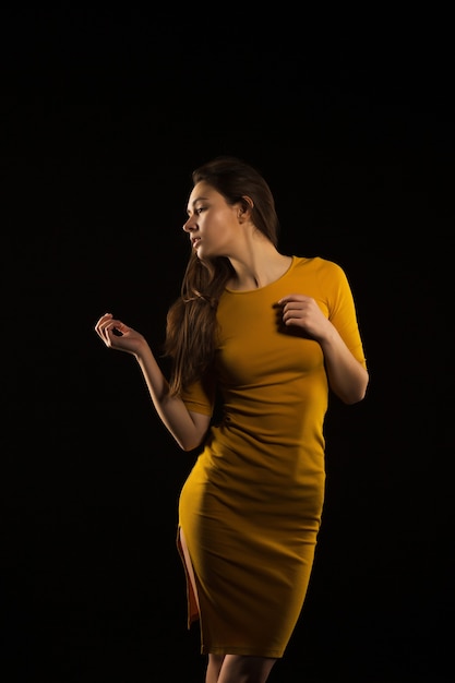 Incroyable femme brune aux cheveux longs posant en robe jaune dans l'ombre