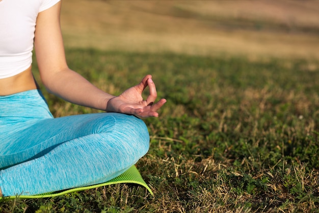 Incroyable femme brune faisant des exercices de yoga sur fond de prairie. Espace pour le texte