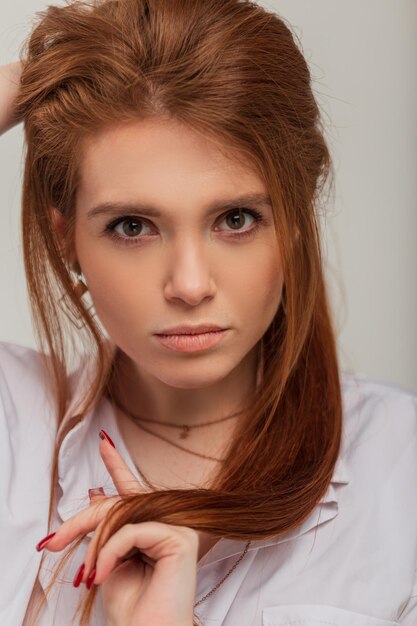 Incroyable headshot portrait féminin d'élégante belle rousse avec un visage frais et propre et des soins de la peau en chemise blanche à la mode