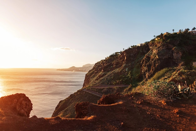 Incroyable île volcanique de Madère dans l'océan au coucher du soleil Montagnes et rochers avec des maisons et une route au bord de l'océan avec un beau coucher de soleil