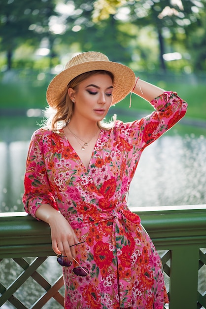 Incroyable jeune femme avec robe et chapeau près d'une fontaine