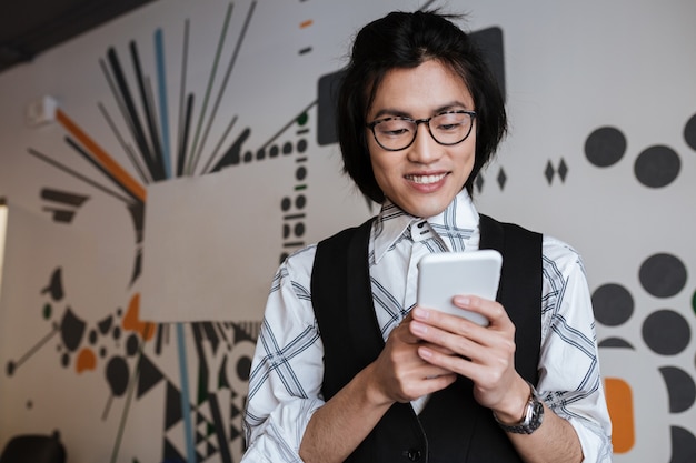 Incroyable jeune homme asiatique à l'aide de téléphone portable à l'intérieur