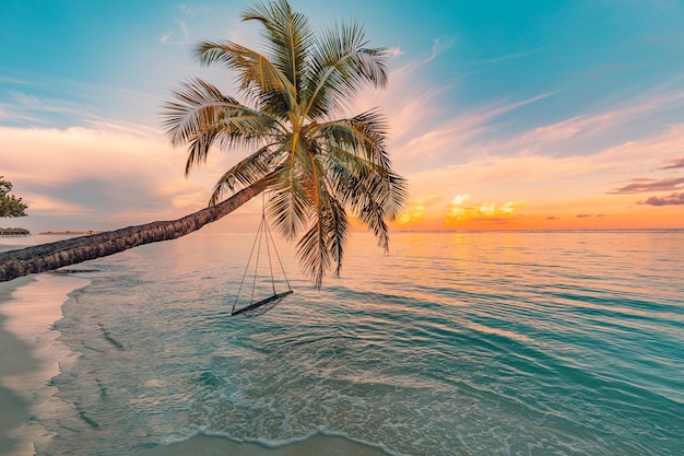 Incroyable nature de plage, motif tropical idyllique, palmier avec balançoire au-dessus d'un lagon de mer calme, vue sur le coucher du soleil