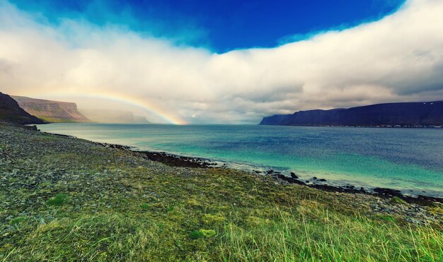 Incroyable paysage d'été avec des nuages blancs de la mer bleue et arc-en-ciel Islande Europe