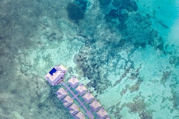 Incroyable vue d'oiseau aux Maldives. Villas sur l'eau de luxe et magnifique lagon de la baie de la mer des récifs coralliens