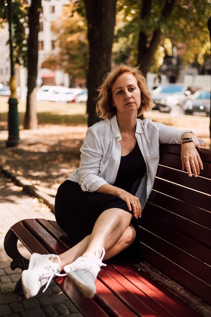 Indépendant de la belle jeune femme assise sur un banc de parc