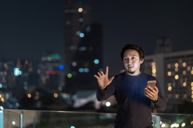 Indépendant créatif asiatique utilisant un téléphone mobile intelligent avec action de sourire dans le quartier financier