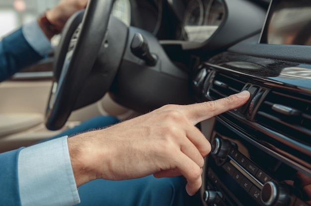 Index de l'homme touchant le système multimédia sur le tableau de bord de la voiture