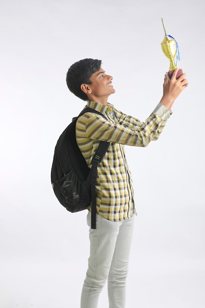 Indian college boy montrant le trophée et donnant l'expression sur fond blanc