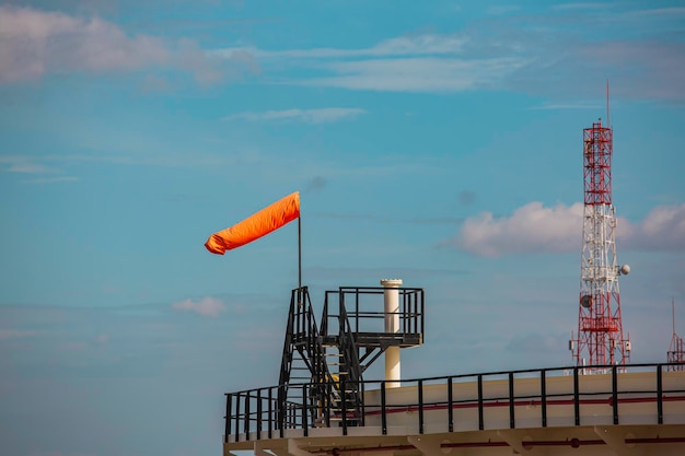 Indicateur de manche à air du vent sur le cône chimique du réservoir indiquant la direction et la force du vent Girouette à manche à air volant horizontalement avec un ciel nuageux en arrière-plan