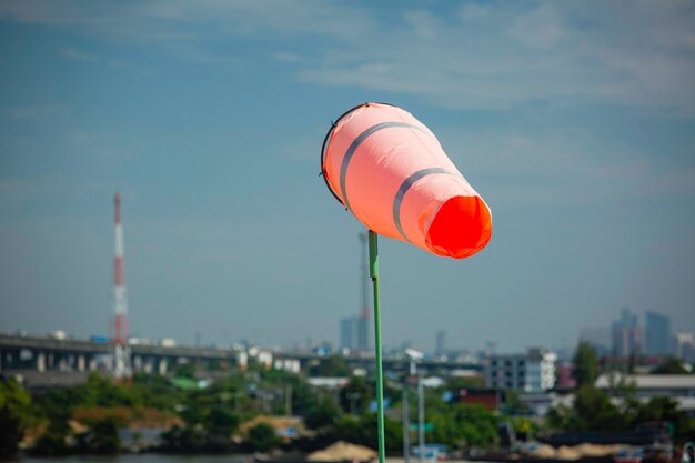 Indicateur de manche à air du vent sur le cône chimique du réservoir indiquant la direction et la force du vent. Manche à air volant horizontalement (girouette) avec ciel nuageux en arrière-plan.