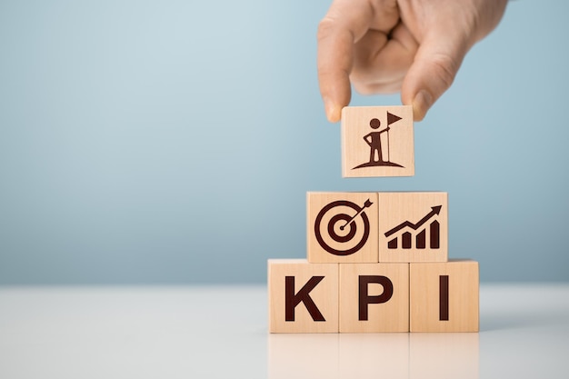 Indicateur de performance clé KPI L'homme d'affaires détient un cube avec un indicateur de performance clé KPI KPI augmente l'optimisation des activités Planification d'entreprise et mesure de la réussite des objectifs