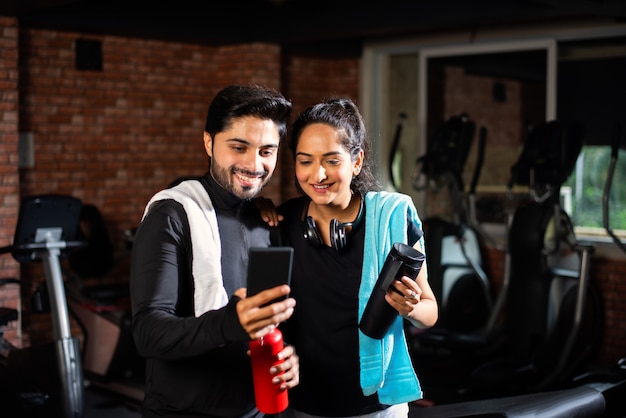 Indien asiatique Jeune couple travaille dans la salle de gym. Une femme séduisante et un bel homme en forme s'entraînent dans une salle de sport moderne - concept de santé et de remise en forme