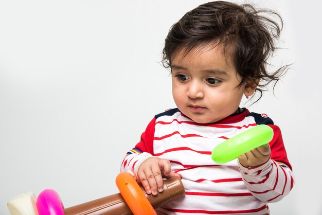 Indien mignon petit bébé ou nourrisson ou tout-petit jouant avec des jouets ou des blocs sur fond blanc,