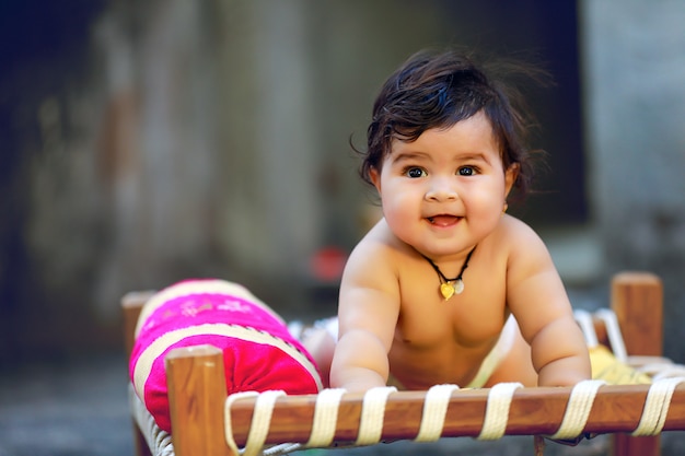 Indien mignon petit enfant sourire et jouer sur un lit en bois