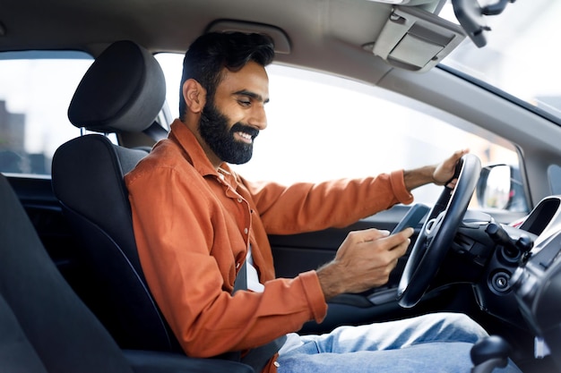 Un Indien utilise des messages sur son smartphone pendant qu'il conduit une voiture.