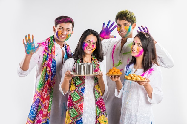 Indiens célébrant holi avec du laddu sucré, des couleurs en thali et des éclaboussures de couleurs