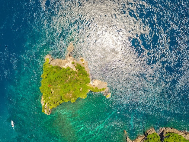 Indonésie. Petite île déserte rocheuse, envahie par la jungle. Bateau à moteur à proximité. Vue aérienne